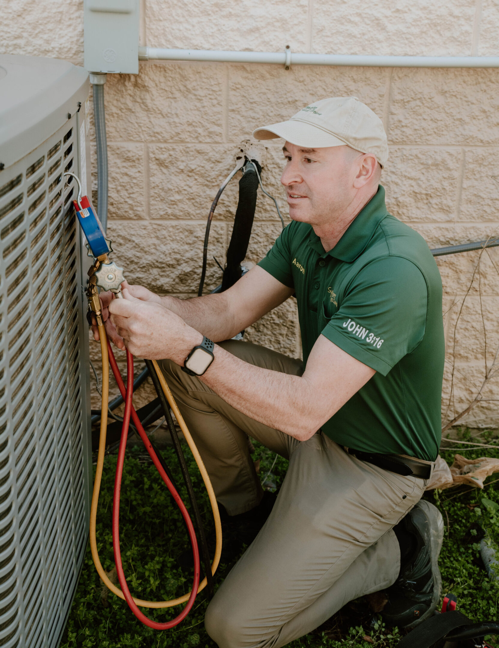 sycamore pic_Aaron A man in green shirt fixing air conditioner.